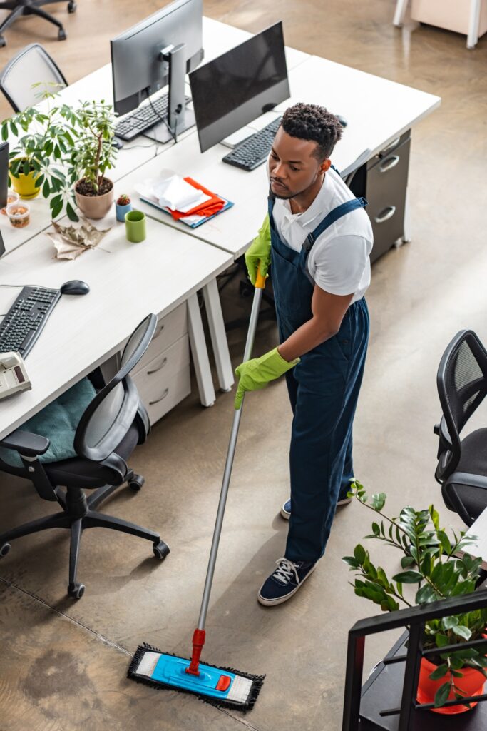 high angle view of african american cleaner washing floor with mop in office